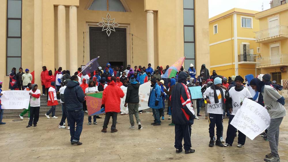 La protesta di un centinaio di eritrei davanti alla chiesa di Lampedusa. I migranti rifiutano di farsi prendere le impronte digitali, come impongono le norme comunitarie, Lampedusa, 6 gennaio 2015. ANSA/ FRANCESCO TERRACINA
